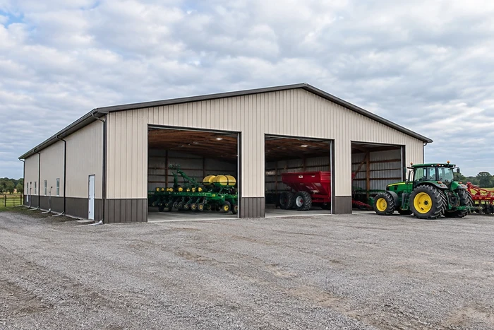 Equipment storage barn with tall openings and a wide gravel maneuvering area.