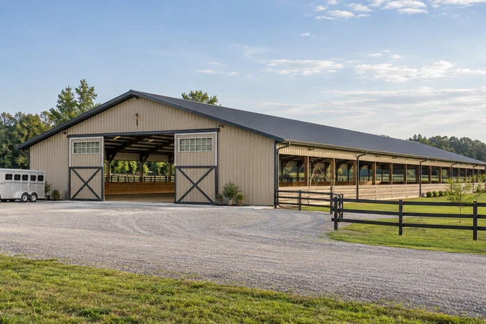 Covered riding arena with broad access doors and an open trailer approach.